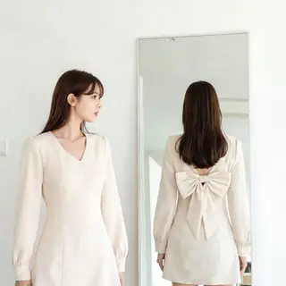 A woman standing in front of a full-length mirror, her refle