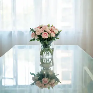 A vase of flowers on a glass table with a clear reflection v