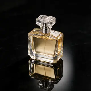 A clear glass perfume bottle on a reflective black surface w