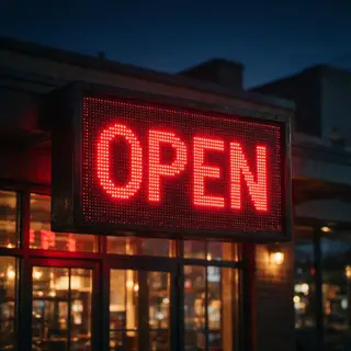 The word 'OPEN' displayed on a red LED sign with glowing pix
