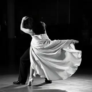 Two tango dancers in a close embrace, the man dipping the wo