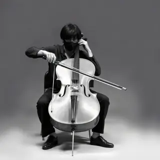 A cellist seated with correct posture, legs around the instr