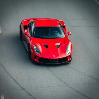 A bright red sports car parked on a gray asphalt road — the 