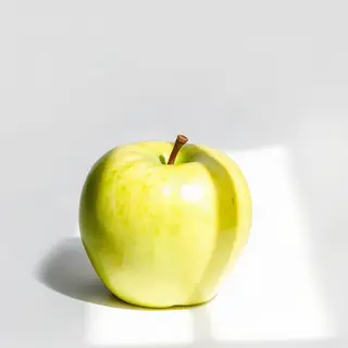 A ripe green apple on a seamless white background with soft 
