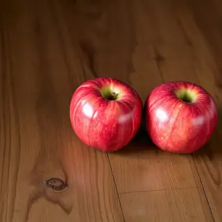 Exactly 3 red apples arranged on a wooden table