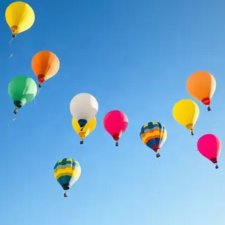 Exactly 11 colorful balloons floating against a clear blue s