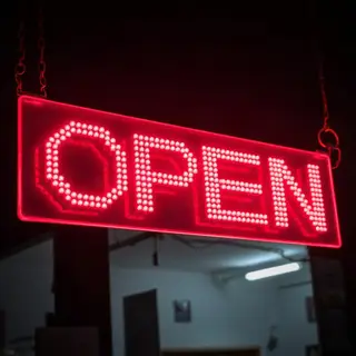 The word 'OPEN' displayed on a red LED sign with glowing pix