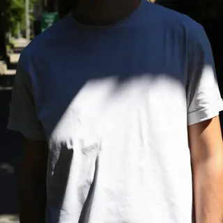 A person standing outdoors at midday with a short shadow dir