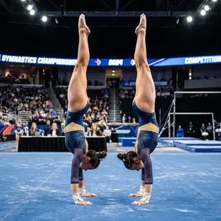 Two gymnasts performing a synchronized handstand, side by si