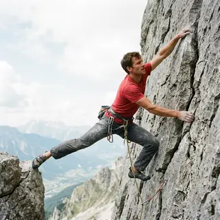 A rock climber clinging to a cliff face with arms and legs e