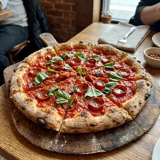 A pepperoni pizza with tomato sauce, basil, and crust but ab