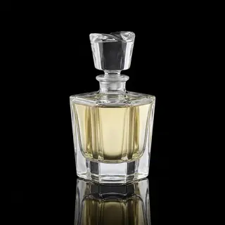 A clear glass perfume bottle on a reflective black surface w