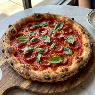A pepperoni pizza with tomato sauce, basil, and crust but ab