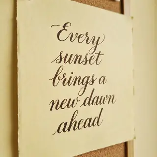 'Every sunset brings a new dawn ahead' written neatly on a p
