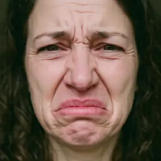 A close-up of a person's face showing clear disgust, nose wr