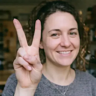 A person making a peace sign with their right hand, clearly 