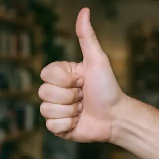 A hand giving a thumbs-up with four fingers curled and thumb