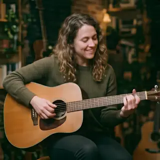 A person playing an acoustic guitar with left hand on the fr