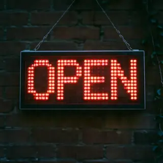 The word 'OPEN' displayed on a red LED sign with glowing pix