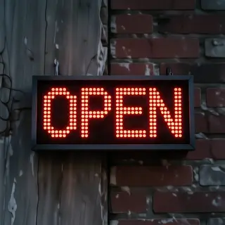 The word 'OPEN' displayed on a red LED sign with glowing pix