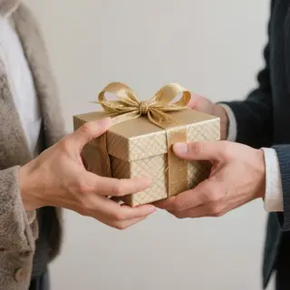 One person handing a small gift box to another person, both 