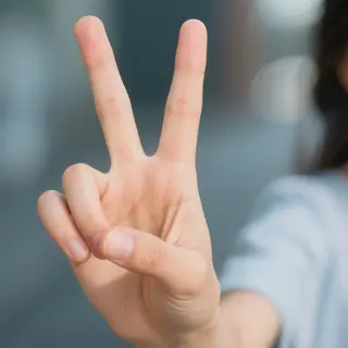 A person making a peace sign with their right hand, clearly 