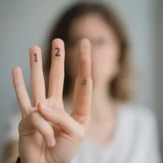 A person counting to three on their fingers, with index, mid
