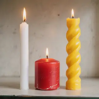 A tall thin white candle, a short fat red candle, and a medi