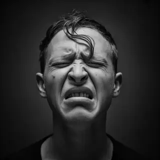A close-up of a person's face showing clear disgust, nose wr