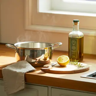 A kitchen counter with a stainless steel pot, a wooden cutti