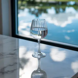 A crystal wine glass on a polished marble counter next to a 