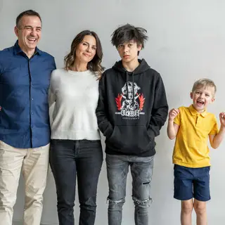 A family photo with four people: a father beaming with pride