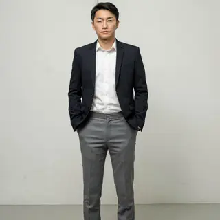 A man standing straight facing the camera, hands in pockets,