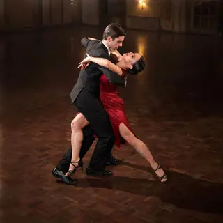 Two tango dancers in a close embrace, the man dipping the wo