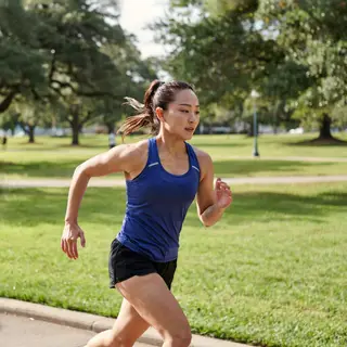 A woman mid-stride running through a park, hair and clothes 