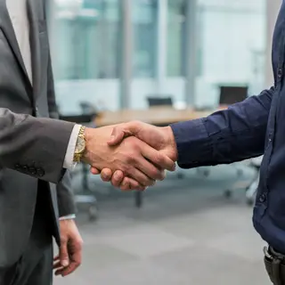 Two people shaking hands in a professional setting, all fing