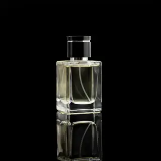 A clear glass perfume bottle on a reflective black surface w