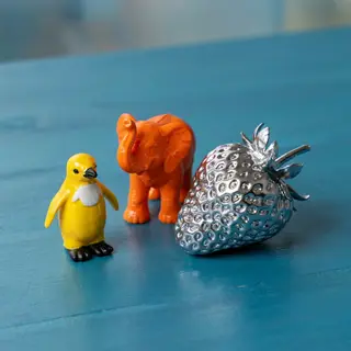 An orange elephant, a yellow penguin, and a silver strawberr