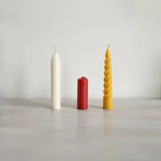 A tall thin white candle, a short fat red candle, and a medi