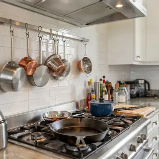 A kitchen with pots, pans, a stove, and a cutting board but 