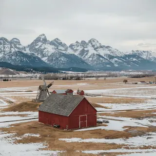 A landscape with a red barn in the foreground at large scale