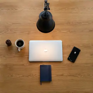 A desk scene: laptop in the center, coffee mug to the left, 
