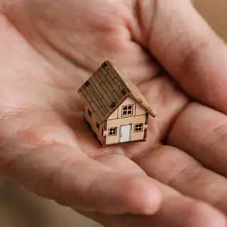 A miniature house sitting on the palm of someone's hand
