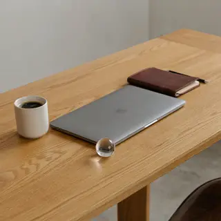 A workspace desk with a brushed aluminum laptop, a leather-b