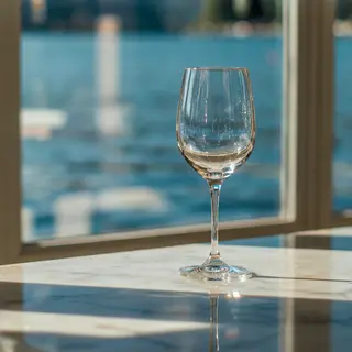 A crystal wine glass on a polished marble counter next to a 