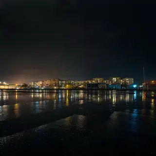A city skyline reflected in a rain puddle on a street, with 