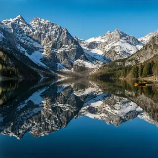 A mountain range reflected in a still alpine lake, with the 