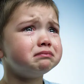A 5-year-old child with round cheeks and large eyes, crying 