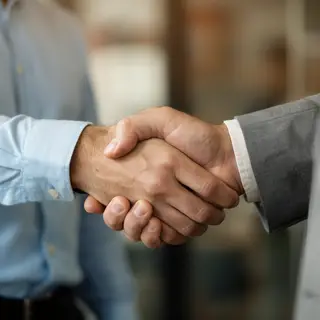 Two people shaking hands in a professional setting, all fing