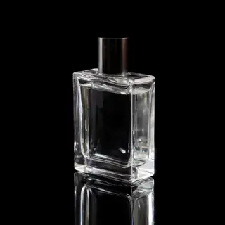 A clear glass perfume bottle on a reflective black surface w